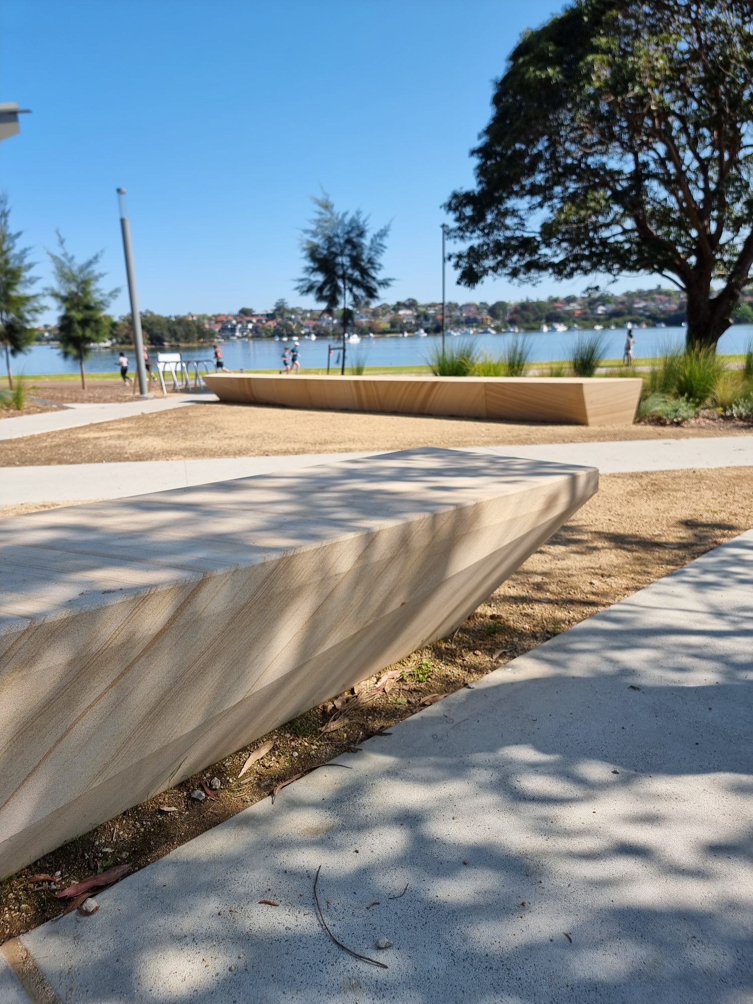 Smooth-cut CNC custom sandstone block seating lining the Barangaroo waterfront promenade, supplied by Gosford Quarries for a premium civic landscaping project.