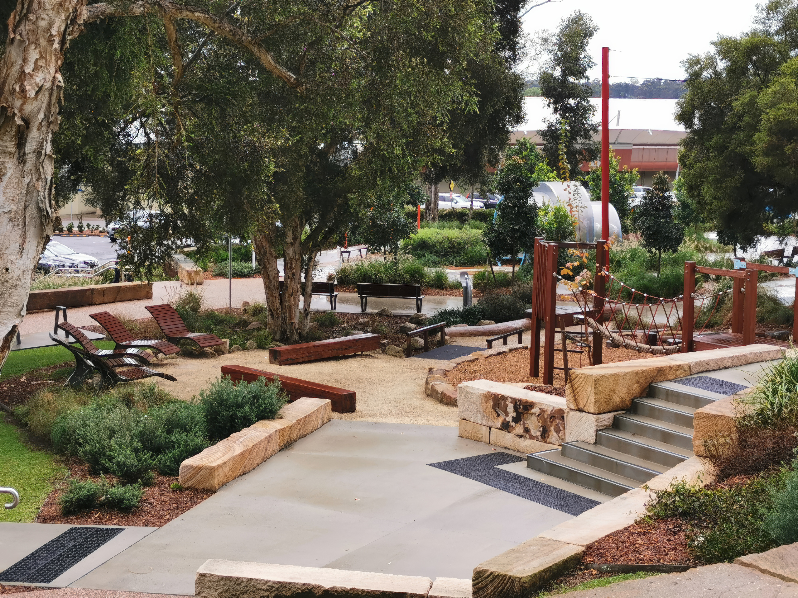 Civic sandstone walls at Bridges Hill Park Playground in Cessnock, with Wonnarua Country welcome signage and integrated landscaping.